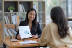 Two woman sitting across from each other looking at a graph representing myCOI Certificate of insurance for events